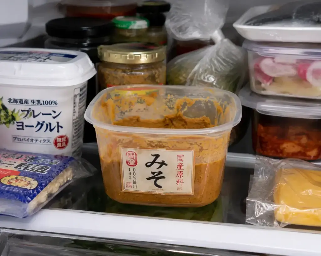  improperly stored miso paste exposed to air on a cluttered refrigerator shelf